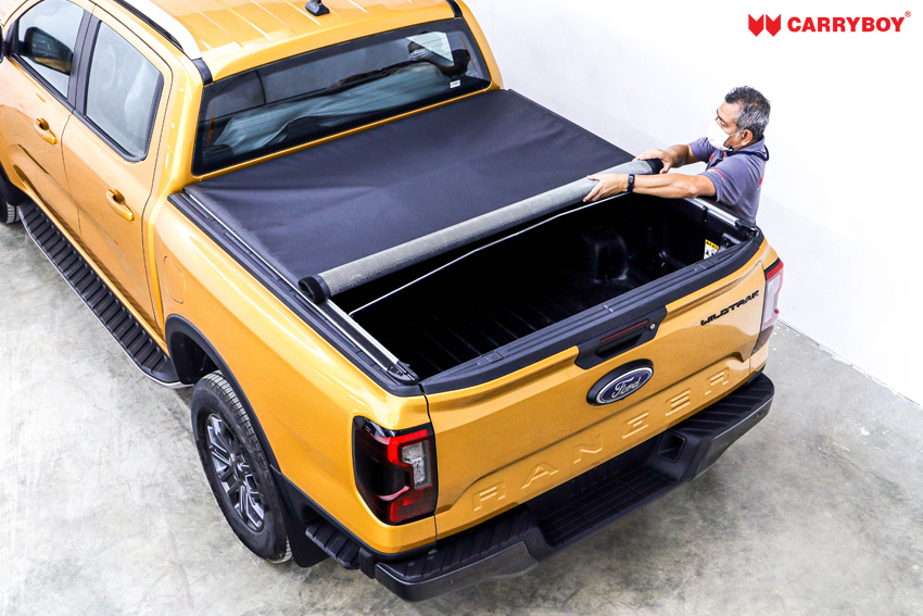 Man rolling the CB-743 Softlid open from the tailgate of a yellow Ford Ranger