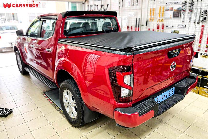 Red Nissan Navara double cab with the Softlid closed in a fitting shop